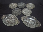 Sete petisqueiras em vidro moldado, lapidado com risos e estrelados, sendo 2 ovais e 3 redondas. 16 x 26cm e 15cm.