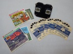 COLECIONISMO - Stereoscope View-Master em baquelite preto e 5 discos de fotos com efeito tridimensional e 2 de histórias com 3 discos cada, "The Love Bug" e "Smokey Bear". Década de 40.