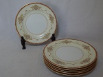 NORITAKE - Seis pratos rasos em porcelana japonesa, borda com esmaltagem bege, medalhões de buquê de flores circundado por volutas e acantos interligados por guirlandas, friso grená. Marcado no fundo. Diam. 26,5cm.