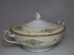 NORITAKE - Terrina em porcelana japonesa, borda com esmaltagem bege, medalhões de buquê de flores circundado por volutas e acantos interligados por guirlandas, friso grená. Pega em pinha. Marcado no fundo. Alt. 15cm.