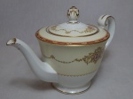 NORITAKE - Bule para chá em porcelana japonesa, borda com esmaltagem bege, medalhões de buquê de flores circundado por volutas e acantos interligados por guirlandas, friso grená. Marcado no fundo. Pega em pinha. Alt. 16cm.