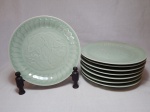 Oito pratos rasos em porcelana chinesa celadon vitrificada em verde oliva, centro decorado com figuras de peixes em sutil relevo. Diâm. 21cm.