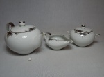 Parte de serviço para chá em porcelana branca japonesa, decoração de frisos prateados representando folhagens. Composto por bule para chá, leiteira baixa e açucareiro. Quebrado na ponta do bico do bule. Marcado Nunome, Japão. Alt. maior 14cm.