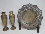 Três peças em metal amarelo: a) Fruteira facetada cinzelada com acantos, borda com vazados. Diâm. 28cm. b) Par de vasos, faixa decorada com rosas em alto relevo. Alt. 20cm.