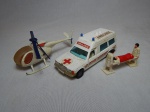 Duas réplicas miniatura de veículos de resgate: a) Ambulância Mercedes-Benz Bonna 2500, manufatura inglesa Corgi, comp. 15cm. b) Helicóptero de resgate em metal esmaltado de branco, com corda de resgate. Hélices no estado. Comp. 14cm.