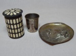 Três peças em metal prateado: porta-cartões moldado no fundo com cena de trabalhadores rurais, 15 x 13cm; pote aplicado com placas de osso, alt. 10cm; copinho, alt. 7cm. Todas com desgastes do tempo.