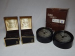 Quatro brindes promocionais da Petrobrás: a) Dois isqueiros de mesa preto e dourado. Embalagem original. 5,5 x 8cm cada. b) Dois relógios de mesa a quartzo, caixa em plástico rígido. Manufatura Eska. Embalagem original. Alt. 9 x diam. 12cm. Funcionamentos desconhecidos.