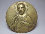 Medalhão em metal amarelo moldado com figura do Sagrado Coração de Jesus. Suporte para apoiar em mesa. Diam. 24,5cm.
