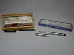 Duas canetas esferográficas: a) "Sun Light" Electric Pen. Não testada e sem garantias. Comp. 14cm. b) Preta e dourada em  estojo de madeira com logomarca da Petrobras. Comp. 14cm.