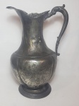 Antiga jarra em metal, decoração em sutil alto relevo de acantos, formato inclinado. No estado. Alt. 37cm.