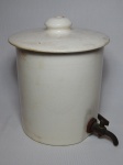 Antiga talha em faiança bege, tampa craquelada, torneira em metal. Leves lascados na borda da tampa. Alt. 24cm.