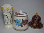 Três peças em cerâmica: vaso com flores moldadas na pasta, pote com flores pintadas à mão e açucareiro marrom decorado com abelhas (apresenta bicados). Alts. 20, 19 e 15cm.