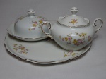 Parte de conjunto para chá em porcelana nacional branca, composto por bandeja, manteigueira e açucareiro, decorado com filetados a ouro e arranjos florais policromados. Marcados Renner. Diâm. bandeja 28cm.