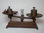 Antiga balança de precisão em ferro fundido, acompanha 5 pesos distintos. Apresenta oxidação. 17 x 28 x 8cm.