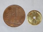 Duas peças: a) Medalha em metal cobreado "SUAPE" Complexo Industrial Portuário, Pernambuco - Brasil. Diam. 19,5cm. b) Medalha em metal amarelo com ideogramas. Diam. 7cm.