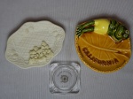 Três peças: a) Saboneteira em biscuit aplicado com flores, fundo em treliça. 14,5 x 11cm. b) Cinzeiro em porcelana vitrificada e moldada com sapo deitado sobre folha, inscrição Califórnia. Diam. 13cm. c) Cinzeiro em vidro translúcido, no fundo a inscrição "Dolder Grand Hotel Zurich. 7 x 7cm.