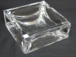 DAUM - Cinzeiro francês em grosso bloco de cristal. Assinado Daum, France. Com quebrados. 13 x 13cm.