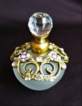 Perfumeiro em vidro satinado com acabamentos em metal cinzelado ricamente ornado com pedras lapidadas e com tampa lapidada ao estilo diamante. Medida 8,5cm de altura.