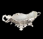 IMPÉRIO AUSTRO HÚNGARO - BOWL DE SERVIÇO PARA UVAS EM PRATA DE LEI FENESTRADA. MARCAS PARA O IMPÉRIO AUSTRO HÚNGARO NO ANO DE 1860. BORDA RECORTADA COM FEITIO DE PARRAS COM TRONCO E FOLHAS E MUITOS CACHOS DE UVAS. AS FENESTRAS SÃO CONSTRUÍDAS EM CRUZ. ALÇAS LATERAIS DUPLAS SEGUEM O MESMO PADRÃO DE DECORAÇÃO SIMULANDO PARRAS COM SEUS FRUTOS. REQUINTADOS E ELEVADOS PÉS REALÇAM A ELEGÂNCIA DA PEÇA. ÁUSTRIA, ANO DE 1860.