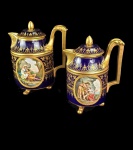 PORCELANA DE VIENA  LINDO CONJUNTO COM DOIS BULES ESTILO IMPÉRIO EM PORCELANA SENDO UM PARA CAFÉ E OUTRO PARA CHOCOLATE. FUNDO NA TONALIDADE AZUL COBALTO REMATADOS EM PROFUSO OURO FORMANDO GUIRLANDAS. NA PARTE POSTERIOR CONTÉM RESERVAS COM DOIS PÁSSAROS E RAMAGENS SIMBOLIZANDO AMOR. FRONTALMENTE DUAS RESERVAS COM PERSONAGENS DE HISTÓRIAS MITOLÓGICAS DE TÓRRIDAS PAIXÕES SENDO EM UM DELES REPRESENTADOS A DEUSA EOS E O REI CÉFALO E NO OUTRO O DEUS BACO E ARIADNE. PEÇAS DE COLECIONADOR! VIENA. 16 CM DE ALTURA (A CHOCOLATEIRA)NOTA: EOS E CÉFALO - Eos , na mitologia grega, é a deusa que personificava o amanhecer. Filha de Hiperião e Teia, é a irmã da deusa Selene, a Lua, e de Hélio, o Sol. Normalmente citada como de longos cabelos louros e unhas tingidas de rosa com uma carruagem purpúrea puxada por dois cavalos alados, Lampo e Faetonte, com arreios multicolores. Ágil e graciosa, é munida de asas nos ombros e nos pés. Essa caracterização expressa seu carácter de jovem caprichosa e despreocupada, que vive amores intensos e efêmeros. Eos tem, como principal função, abrir as portas do céu para a carruagem de Hélio, a personificação do Sol, sendo assim a deusa do amanhecer (Quando a carruagem de Hélio está saindo, e o Sol está nascendo) e do entardecer, mais especificamente, o pôr do sol (Quando a carruagem de Hélio está voltando, e o Sol está se pondo). Responsável também pelo brilho do Sol e das tonalidades do Céu, Eos é a deusa que desperta as pessoas e criaturas dos mais profundos sonhos e derrama orvalho nas folhas, sendo mais conhecida por ser a deusa especialmente do amanhecer. Céfalo, filho de Hermes e Herse, também foi vítima do amor implacável de Eos.  Ele estava já casado com a princesa Prócris, terna e amorosa e sempre fiel a seu marido. Insaciável como sempre, Eos pouco se importa para o sofrimento de Prócris e rapta Céfalo enquanto caçava nas proximidades do monte Imeto. Mas apesar de todos os esforços da deusa, o jovem continua apaixonado por sua esposa. Apesar de muitos esquemas ardilosos da deusa, Céfalo e Prócris se reconciliam. Céfalo volta a caçar, mas sua esposa, com receando a deusa rival, o segue. Pensando se tratar de um animal, ele a mata e ao ver o que havia feito, se joga ao mar. Comovido, Zeus os transforma em estrelas. BACO E ARIADNE  Ariadne era filha do rei Minos, depois de ajudar Teseu a fugir do labirinto quando o herói matou o minotauro, foi raptada por ele e levada a ilha de Naxos e lá foi deixada dormindo, enquanto o ingrato Teseu fazia o caminho de volta para casa sem ela. Ariadne, quando acordou e viu que tinha sido abandonada, entregou-se à desilusão. Mas Vênus compadeceu-se dela, e a consolou com a promessa de que teria um amor imortal, no lugar do mortal que ela havia perdido. A ilha onde Ariadne foi deixada era a ilha favorita de Baco. Como Ariadne estivesse lamentando sua sorte, Baco a encontrou, a confortou, e fez dela sua esposa. Como presente de casamento, ele ofereceu a ela uma coroa de ouro, repleta de pedras preciosas, e quando ela morreu, ela levou consigo a coroa, atirando-a para o céu. A medida que subia as pedras preciosas foram se tornando mais brilhantes e se transformaram em estrelas, e preservando a própria forma, a coroa de Ariadne se fixou no espaço celeste como uma constelação, entre Hercules de joelhos e o homem segurando a serpente.