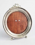 LINDO PORTA RETRATOS EM PRATA DE LEI COM FUNDO EM MADEIRA (FORMA PAR COM O DO LOTE SEGUINTE). FEITIO CIRCULAR. ELEGANTE DECORAÇÃO REMATADA POR LAÇAROTE NO TOPO. EUROPA, INICIO DO SEC. XX.  17,5 CM DE ALTURA