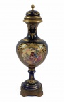SEVRES - BELA ÂNFORA EM PORCELANA NA TONALIDADE AZUL ROYAL COM RICA ORNAMENTAÇÃO EM OURO RELEVADO E GUARNIÇÃO EM BRONZE ORMOLU. NA PARTE FRONTAL E POSTERIOR RESERVA SENDO CENA GALANTE DE UM LADO E MANSÃO CAMPESTRE COM LAGO NO OUTRO. ASSINADA PELO ARTISTA. FRANÇA, SEC. XIX. 39 CM DE ALTURA