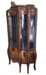 VERNIZ MARTIN - PALACIANA VITRINE EM MADEIRA ESTILO LOUIS XV. INCOMUM PELA GRANDE DIMENSÃO MAS TAMBÉM PELA BELEZA E ELEGÂNCIA. TRABALHO EXCEPCIONAL COM RICA BRONZERIA ORMOLU COMPOSTA DE CARIÁTIDES, ROCAILLES VEGETALISTAS E MOLDURAS. SUAVE MOVIMENTO BOMBE E CONTRA BOMBE. LINDAS PINTURAS ASSINADAS PELO ARTISTA COM CENAS DE PALÁCIO COM SEUS JARDINS E PERSONAGENS COM TRAJES DE CORTE. FEITIO RECORTADO. TETO ABOBADADO. LINDA FORRAÇÃO INTERNA EM AZUL. FRANÇA, SEGUNDA METADE DO SEC. XIX. 204 (H) X 115 (C) X 45 (P) CMNOTA: No design de interiores francês , Verniz Martin é um tipo (ou vários tipos) de laca japonesa , nomeada após os irmãos Martin franceses do século XVIII: Guillaume (falecido em 1749), Etienne-Simon, Robert e Julien se tornarem grandes fornecedores de móveis utilizando essa tecnica. Eles dirigiram uma fábrica entre 1730 e 1770 e eram vernisseurs du roi ("envernizadores do rei"). Mas eles não inventaram o processo, nem foram os únicos produtores, nem o termo abrange uma única fórmula ou técnica. Imitava laca chinesa sobre temas europeus, e era aplicada a uma ampla variedade de itens, de móveis a carruagens . Na composição de seu verniz, os Martins usam uma resina tóxica - chamada copal - importada do Brasil e do Ceilão; mas sua grande habilidade reside - como os japoneses - em misturar este copal com pó de ouro ou limalha de bronze para obter superfícies pigmentadas. Ainda mais essencial na técnica, está a exposição do verniz, processo pelo qual os Martins obrigam seus trabalhadores ao verdadeiro rigor chinês para obterem resultados impecáveis. Portanto, não menos do que quarenta e três camadas de diferentes materiais são necessárias para obter a transparência e a cor desejadas. Os primeiros vinte e três são em branco Meudon cada vez mais fino, estampados na madeira como é a prática para dourar água. Um reparador cinzela com pequenos ferros afiados e torneados e restaura na espessura das camadas o seu brilho à escultura. Aplicamos sobre cinco camadas de camadas amaciadas com uma palheta. Finalmente, iremos envernizar e polir cinco vezes consecutivas.