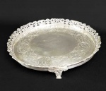 SALVA EM PRATA DE LEI COM FEITIO CIRCULAR. MARCAS DE CONTRASTE DO PRATEIRO SP TEOR 800. GALERIA VAZADA COM DECORAÇÃO DE FLORES E RAMAGENS. PLANO DECORADO COM MAGNIFICOS CINZELADOS CONSTITUINDO ROCAILLES VEGETALISTAS. ASSENTE SOBRE TRES PÉS EM GARRA. BRASIL, MEADOS DO SEC. XX. 25 CM DE DIAMETRO. 620 G