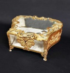 LINDA CAIXA EM BRONZE ORMOLU COM VIDROS BIZOTADOS NA TAMPA, NA FRENTE E ATRÁS. ESTILO E ÉPOCA NAPOLEÃO III. DECORADA COM RAMAGENS E FRUTOS DE LOURO EM RESERVA. ELEVADA SOBRE QUATRO PÉS. FRANÇA, SEGUNDA METADE DO SEC. XIX. 20 CM DE COMPRIMENTO.
