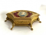 GRANDE CAIXA COFRE EM BRONZE ORMOLU DECORADA COM ESMALTE LIMOUSIN E RESERVA CENTRAL COM PINTURA SOBRE MARFIM REPRESENTANDO PERSONAGEM FEMININO. ELEGANTE FEITIO, BRONZE DE EXCEPCIONAL QUALIDADE COM FLORES E GUIRLANDAS RELEVADAS. ASSENTE SOBRE PÉS COM FEITIO DE CAPRICHADAS GARRAS E FOLHAS DE ACANTO. A PINTURA TEM ASSINATURA COM MONOGRAMA. O RETRATO É EMOLDURADO POR MAGNIFICO ESMALTE DE LIMOGES NA TONALIDADE VERMELHA. FRANÇA, SEC. XIX. 37 CM DE COMPRIMENTO.