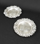 DOIS COASTERS PARA GARRAFAS EM PRATA DE LEI. DECORADO COM ELEMENTOS VEGETALISTAS COM FLORES E ROCAILLES PORTUGAL, INICIO DO SEC. XX. 14 CM DE DIAMETRO