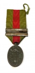 GUERRA DO PARAGUAI -  MEDALHA RECOMPENSA A BRAVURA MILITAR  RARA MEDALHA EM BRONZE COM SUA FITA ORIGINAL E DOIS PASSADORES POR BRAVURA EM DUAS BATALHAS DA GUERRA DO PARAGUAI. CRIADA POR D. PEDRO II PELO DECRETO 4131 DE 28 MAR 1868, DESTINADA AOS  QUE SE DEM0NSTRARAM  DIGNOS POR ATOS DE BRAVURA EM AÇÕES  DE GUERRA DURANTE A CAMPANHA DO PARAGUAI. A MEDALHA É  OVAL, DE BRONZE E USADA DO LADO ESQUERDO DO PEITO, PENDENTE DE FITA COM TRÊS LISTRAS, UMA ESCARLATE CENTRAL E COMO EXTREMAS VERDES. ELA POSSUÍA TANTOS PASSADORES QUANTOS ERAM COMO CONCESSÕES POR AÇÕES EM QUE PRATICOU ATO DE BRAVURA. AS AÇÕES FIGURAVAM PELA DATA, OU PELO NOME HISTÓRICO QUE TOMOU A AÇÃO. ESSA MEDALHA EM PREGÃO FOIS CONCEDIDA POR ATOS EM DUAS BATALHAS (TEM DOIS PASSADORES COM AS DATAS CORRESPONDENTES AS BATALHAS DE NHU-GUAÇU TRAVADA EM 16 DE AGOSTO DE 1869 E TAMBÉM POR ATOS NA BATALHA DE PIRIBEBUY, TRAVADA EM 12 DE AGOSTO DE 1869). POSSUI ALÉM DA FITA A PARTE INFERIOR DA CAIXA ORIGINAL. O ANVERSO TEM: UM CONJUNTO DE TROFÉUS DE GUERRA COM CANHÕES, BANDEIRAS E BALAS DE CANHÃO CIRCUNDADO PELA LEGENDA - EXÉRCITO EM OPERAÇÃO CONTRA O GOVERNO DO PARAGUAY. O REVERSO APRESENTA: INSCRIÇÃO CENTRAL RECOMPENSA À BRAVURA MILITAR, CIRCUNDADO PELA INSCRIÇÃO DECRETO DE 28 DE MARÇO DE 1868. BRASIL, 1869, 10 CM DE COMPRIMENTO COM A FITA, SEM CONSIDERAR O TAMANHO DA FITA: 4,3 CM DE COMPRIMENTO.NOTA: A Guerra do Paraguai (1864-1870) foi o maior e o mais sangrento conflito de toda História da  América do Sul. O Brasil liderou as operações de Guerra em conjunto com a Argentina e Uruguai contra o Ditador do Paraguai Solano Lopes. Vamos discorrer um pouco sobre as duas batalhas cujos atos de bravura laurearam o soldado que recebeu essa medalha em pregão: BATALHA DE PIRIBEBUY, TRAVADA EM 12 DE AGOSTO DE 1869: A Batalha de Piribebuy  foi travada em 12 de agosto de 1869 na cidade paraguaia de Piribebuy, que era então uma porção como uma capital temporária do governo paraguaio. Os defensores paraguaios, que estavam mal armados e incluíam crianças, lutaram contra os ataques das forças aliadas, lideradas pelo general brasileiro CONDE DEU, marido da PRINCESA ISABEL e genro do IMPERADOR PEDRO II do Brasil. O pequeno povoado de Piribebuy, a pouco mais de 70 km a oeste de Asunción, encontrava-se na encosta de um cerro, cercados por colinas mais elevadas. Possuía humildes casas de tetos de palha e uma igreja colonial telhada. A vila era defendida por um fosso e trincheira de leiva, sob a forma de polígono irregular de 28 faces, de 2.422 metros de circunferência. Um córrego cortava Piribebuy, desaguando no arroio homônimo (Taunay, 2002, p. 134 et seq.). No central, forças aliancistas, de vinte mil imperiais e argentinos e mais de trinta canhões, cercaram a vila em 10 de agosto de 1869, onde se encontravam 1.600 defensores, no geral hombres mal armados, la mayor parte muchachos.(homens mal armados e crianças)  No dia 11, após posicionar suas forças, o conde dEu teria intimado à rendição a Pedro Pablo Caballero. O comandante da vila teria respondido com palavras de aço:  Estoy aquí para pelear, y si es necesario morir; pero no para rendirme (Centurión, 2010, p. 393-94). Na madrugada do dia 12, antes que iniciasse o bombardeio, o conde dEu mandara novamente delegado intimar a Caballero para que retirase del recinto del reducto a las mujeres y a los niños. Novamente Pedro Pablo Caballero respondera em forma altiva: Decid a vuestro jefe que las mujeres y los niños están aquí seguros, y que él mandará en territorio paraguayo cuando no haya uno que lo defienda! Destaque-se que mulheres e crianças eram boa parte das tropas defensoras da vila. A seguir, teria iniciado o ataque, de resultados já certos, devido ao enorme desequilíbrio de forças  treze soldados aliancistas para cada paraguaio! Y sin embargo la resistencia fue heroica y prolongada. Duró 5 horas!. Segundo aquele autor, as tropas aliancistas teriam atacado em forma mais encarniçada pelo norte, posição que sabiam guarnecida por cuerpos compuestos de muchachos débiles armados los más de escopetas de cazar y lanzas. Como os demais atacantes, o general João Manuel Mena Barreto, montado en un hermoso alazán, teria sido rechaçado dos veces, retirando-se com suas tropas para reorganizar-se, para além do arroio Mboveví. Na terceira investida, a 500 varas c. 550 metros da trincheira, teria sido ferido mortalmente por uma bala de fuzil na ingle, ou seja, na virilha. Transferido para uma cabana próxima, faleceu antes que o cirurgião chegasse. Entrementes, os assaltantes romperam as defesas pelo sul, aprisionando, entre outros, Pedro Pablo Caballero e o chefe político da povoação, Patricio Marecos, conduzidos diante do conde que habló con Caballero. Porém, ao saber que, mesmo não tendo morrido muitos assaltantes, falecera o general Mena Barreto, o comandante em chefe das tropas imperiais teria dito, apontando para os dois prisioneiros diante de si:   Degüéllenlos a esos, ellos tienen la culpa! Ordem que teria sido cumprida imediatamente. Pedro Pablo Caballero teria sido degolado ao lado do cadáver do general sul-rio-grandense  ou o seu cadáver foi exposto junto a ele, mais tarde. Mais tarde, uma testemunha ocular, Asunción Gonzáles, que teria levantado o quepe do chefe paraguaio, constatando o corte ao pescoço, afastou a possibilidade de uma morte em combate. A batalha durou 5 horas, com os aliados, que tinham uma grande vantagem numérica, capturaram a cidade. O hospital da cidade foi queimado com varios feridos dentro do hospital, e os documentos oficiais foram perdidos no fogo resultante, mas  o fogo resultou por conta de um tiro de canhão não intencional. BATALHA DE NHU-GUAÇU: Na batalha seguinte, Campo Grande ou Nhu-Guaçu (16 de agosto), as forças brasileiras se defrontaram com um exército formado, em sua maioria, por adolescentes e crianças e idosos, recrutados a força pelo ditador paraguaio. A derrota paraguaia encerrou o ciclo de batalhas da guerra. Os passos seguintes consistiram na mera caçada a López, que abandonou Ascurra e, seguido por menos de trezentos homens, embrenhou-se nas matas, marchando sempre para o norte. Dois destacamentos foram enviados em perseguição ao presidente paraguaio, que se internara nas matas do norte do país acompanhado de 200 homens. No dia 1.º de março de 1870, as tropas do general José Antônio Correia da Câmara (1824-1893), o Visconde de Pelotas, surpreenderam o último acampamento paraguaio, em Cerro Corá, onde Solano López foi ferido a lança pelo cabo Chico Diabo e depois baleado, nas barrancas do arroio Aquidabanigui, após recusar-se à rendição. Depois de Cerro Corá, as tropas brasileiras ficaram eufóricas, assassinando civis, pondo fogo em acampamentos e matando feridos e doentes que se encontravam nos ranchos. Não era esse o desejo do imperador D. Pedro II, que preferia ter López preso a morto. No Rio de Janeiro, a morte de Lopéz foi muito bem recebida e o imperador recuperou sua popularidade que havia sido abalada pela dispendiosa guerra. Em 20 de junho de 1870, Brasil e Paraguai assinaram um acordo preliminar de paz.