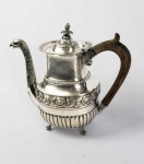 EXTRAORDINÁRIO BULE PARA CAFÉ DE COLEÇÃO EM PRATA DE LEI DE GRANDES DIMENSÕES. MARCAS DE CONTRASTE DO ENSAIADOR MANUEL DA SILVA, USADO EM 1853. BICO DECORADO COM MAGNIFICA CABEÇA DE ÁGUIA DE CUJO PERSCOÇO PENDEM FRANJAS. CORPO DECORADO COM LARGO BARRADO CENTRAL COM FLORES E RAMAGENS DE PAPOULAS. TERÇO INFERIOR TEM GOMADOS E TERÇO SUPERIOR GODRONS RELEVADOS. ELEVADO SOBRE QUATRO CAPRICHADOS PÉS DE GARRA E BOLA. ALÇA EM MADEIRA DECORADA EM CARAPETAS. PORTUGAL, MEADOS DO SEC. XIX. 27 CM DE ALTURA. 1325 G