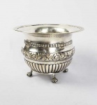 PINGADEIRA OU BOWL DE PINGOS EM PRATA DE LEI DE GRANDES DIMENSÕES. MARCAS DE CONTRASTE DO ENSAIADOR MANUEL DA SILVA, USADO EM 1853. CORPO DECORADO COM LARGO BARRADO CENTRAL COM FLORES E RAMAGENS DE PAPOULAS. TERÇO INFERIOR TEM GOMADOS E TERÇO SUPERIOR GODRONS RELEVADOS. ELEVADO SOBRE QUATRO CAPRICHADOS PÉS DE GARRA E BOLA. PORTUGAL, MEADOS DO SEC. XIX. 34 CM 15 CM DE DIAMETRO. 480 GNOTA: As pingadeiras tinham um importante papel no ritual do chá. Eram usadas para que os participantes do chá vertessem o fundo da xícara que já estava frio para enche-la novamente. Hoje em dia prestam-se como bowls para servir acepipes ou mesmo cachepots para plantas.