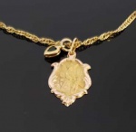 TORNOZELEIRA EM OURO 18 K COM PINGENTE DE CORAÇÃO REMATADO POR ESMERALDA E MEDALHA DE ANJO DA GUARDA. 24 CM E COMPRIMENTO. 1,8 G