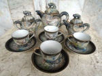 Serviço de café/ chá  em porcelana SATZUMA/JAPAN , decorado com ornamentação de cenas e figuras de  dragões em alto relevo, em fundo cinza degradée  composto  por 01 bule, 01 cremeira, 01 açucareiro e  04 xícaras  com seus respectivos pires.  Muito antigas as peças . Açucareiro com bicado interno na tampa.