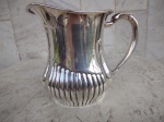 REBOUÇAS : Jarra para suco/água em metal espessurado a prata  com caneluras na base. Medidas Altura 15 cm e largura 18 cm.