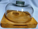 Queijeira em vidro transparente com base em madeira de lei de ótima qualidade . Pode ser usada de duas formas. Medidas 24 x 23 x 3 cm (tábua ) e o vidro 16 de altura x 21,5 cm de diâmetro.