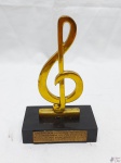 Escultura de nota musical em metal dourado com base em resina, gravado "Ordem dos músicos do Brasil - Homenagem do presidente Dr. Wilson Sandoli". Medindo 18cm de altura.