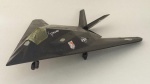 PLASTIMODELISMO - AVIÃO F-117A Nighthawk TR 37 TFW USAF. Sem o pedestal. Feito em plástico, mede aprox. 26,8 centímetros de comprimento. A envergadura das asas mede aprox. 18,3 centímetros.O Lockheed F-117 Nighthawk é um caça-bombardeiro furtivo de um só assento, bimotor, desenvolvido pela divisão de projetos secretos denominada Skunk Works da Lockheed e operado pela Força Aérea dos Estados Unidos (USAF). O F-117 foi baseado no demonstrador de tecnologia Have Blue e foi o primeiro avião operacional a ser projetado em torno da tecnologia furtiva. O voo inaugural do Nighthawk ocorreu em 1981 e a aeronave alcançou sua capacidade operacional em 1983. O Nighthawk ficou envolto em segredo até que ser revelado ao público em 1988. O F-117 foi amplamente divulgado por seu papel na Guerra do Golfo de 1991. Embora fosse comumente referido como o "Stealth Fighter", era estritamente um avião de ataque. Os F-117 participaram no conflito na Iugoslávia, onde um foi derrubado por um míssil terra-ar (SAM) em 27 de março de 1999; foi o único Nighthawk a ser perdido em combate. A Força Aérea dos EUA retirou os F-117 em 22 de abril de 2008, principalmente devido ao F-22 Raptor. Sessenta e quatro F-117 foram construídos, 59 dos quais eram versões de produção, sendo os outros cinco demonstradores/protótipos. O F-117 tem sido utilizado várias vezes em guerras contemporâneas. A sua primeira missão real foi no Panamá, na Operação Justa Causa, em 1989. Durante a invasão, o F-117 largou duas bombas na base de Rio Hato. Mais tarde, durante a Guerra do Golfo, largou bombas inteligentes em alvos iraquianos. Tem sido utilizado, desde então, na Guerra do Kosovo em 1999, no Afeganistão e na Invasão do Iraque.