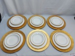 Jogo de 12 pratos em porcelana com friso ouro e 6 sousplats em plástico dourado. Sendo 6 pratos rasos, 6 pratos fundos e 6 sousplats.