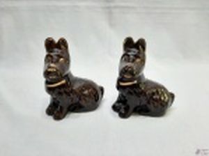 Par de esculturas na forma de cachorro Scottish Terrier sentados em porcelana marrom com ouro. Medindo 14,5cm de altura.