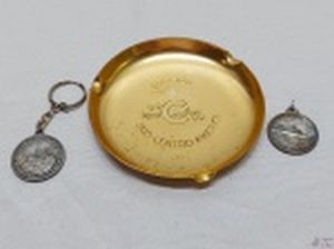 Lote composto de 2 chaveiros com medalhas e um cinzeiro em metal dourado, peças com motivos navais. Medindo o cinzeiro 11,5cm de diâmetro.