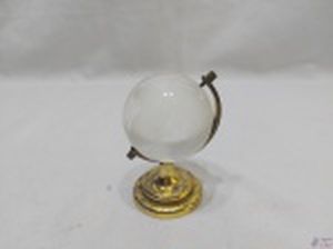 Enfeite na forma de globo terrestre com base em metal dourado e globo em vidro. Medindo 9cm de altura.