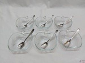 Jogo de 6 cumbucas em vidro na forma de maçã e 6 colheres tipo pá em aço inox. Medindo as cumbucas 12,5cm x 12,5cm x 4,5cm de altura.