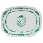 Raríssima travessa retangular de cantos chanfrados em porcelana Cia. das Índias decorada em esmalte de tonalidade verde, tendo ao centro o Brasão de João Luiz de Mello - Capitão Mor de Ponte de Lima e Senhor da Casa do Antepasso - 1785. Cercadura com hastes de bambu e folhagens. Peça idêntica reproduzida no livro A Porcelana Chinesa e os Brasões do Império por Nuno Castro na página 110. Imperador Qianlong (1736-1795), Séc. XVIII. 34,5 x 27 cm de diâmetro. (Devido a fragilidade desse lote, seu envio só será realizado através de transportadora especializada). Chama-se Companhia das Índias a porcelana produzida na China por encomenda e com formas ou decoração ao gosto ocidental, transportada pelos navios das diversas Companhias das Índias - inglesa, francesa, holandesa, sueca etc. -, ativas entre os Sécs. XVII e começos do XIX. Nas porcelanas policromadas, ocorrem dois tipos principais de decoração: a Família Verde, surgida em fins do Séc. XVII sob o reinado do Imperador Kangxi (falecido em 1722), e a Família Rosa, caracterizada pela utilização de um esmalte de cor rósea, surgida mais ou menos em 1720 e que se estenderia por todo o reinado do Imperador Qianlong (1736-1795). Flores, pássaros e figuras humanas constituem a decoração preponderante nessas porcelanas. Além desses dois, existem, porém, outros tipos de decoração policromada, como por exemplo a Família Negra, que consiste na esmaltagem sobre fundo negro; a Café com Leite, na cor castanha, também chamada porcelana de Batávia porque era exportada através do porto de Batávia, em Java; e o Imari chinês, cuja decoração imita as porcelanas japonesas produzidas em Arita, na província de Hizen. Inúmeros serviços de jantar ou de chá e café em porcelana Companhia das Índias foram encomendados por nobres ingleses, franceses, alemães, holandeses, portugueses etc. e exibem suas armas ou brasões. De notar que os portugueses foram os primeiros europeus a encomendar à China peças de porcelana exibindo suas armas, sendo que as mais antigas remontam ao reinado do Imperador Zhengde (1506-1521), da Dinastia Ming.