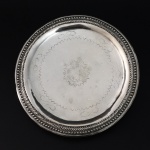 Salva em prata batida, repuxada e perolada de estilo e época D. Maria I. Brasil, cerca de 1810. 200 gr. 19 cm de diâmetro.