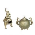 Conjunto de duas esculturas em bronze, sendo uma delas figura oriental sobre animal mitológico e a segunda um incensário com alças em forma de dragão com cenas do cotidiano. China, Séc. XIX/XX. 27 cm de altura a figura e 19,5 cm o incensário.