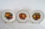 MITTERTEICH, BAVARIA - Trio de pratos em fina porcelana alemã, decorados ao centro com pencas de frutos e borda em dourado, marcado na base. Med. 29 cm cada.