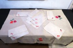 Uma (1) toalha de mesa base retangular, confeccionada em linho na cor marfim com aplicação de flores. Acompanha 12 guardanapos no mesmo padrão .Med. 240 x 145 cm, guardanapos 35 x 35 cm. Com mínima manchas de guardado na dobra.